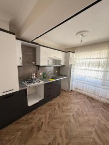 a kitchen with white cabinets and a wooden floor at İlkay suit in Bandırma