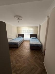 two beds in a small room with wooden floors at İlkay suit in Bandırma