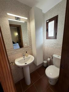 a bathroom with a sink and a toilet and a mirror at Casa Rural Rincón del Lago in El Ronquillo
