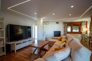 salon z kanapą i telewizorem z płaskim ekranem w obiekcie RentitSpain Grand Luxury Villa Piscina & Jacuzzi Granada w mieście Albolote