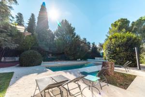 basen z dwoma krzesłami i stołem obok niego w obiekcie RentitSpain Grand Luxury Villa Piscina & Jacuzzi Granada w mieście Albolote