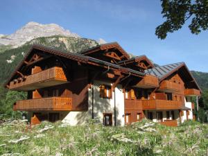 a building with wooden balconies and a mountain at Duplex chaleureux au centre, proche commerces et téléphérique, avec balcon sud et parking couvert - FR-1-464-76 in Pralognan-la-Vanoise