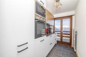 a kitchen with white cabinets and a view of a mountain at Les Rocailles Apartment | 9 in La Tzoumaz