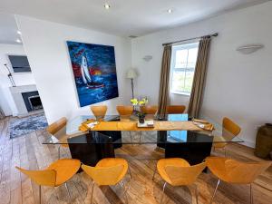a dining room with a glass table and orange chairs at Sheerghlass in Castletown