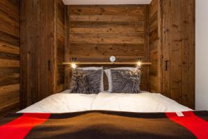 a bedroom with wooden walls and a bed with pillows at Les Rocailles Apartment | 9 in La Tzoumaz