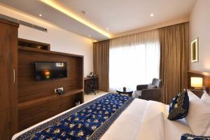 a hotel room with a bed and a flat screen tv at Clubhouse Hotel by CheckIn Morbi in Morbi +13 photos