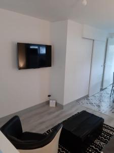 a living room with a black chair and a tv on a wall at Othello Studio in Souillac