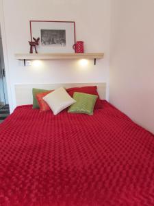 uma cama vermelha com lençóis vermelhos e almofadas verdes em Apartment Grado em Zagreb