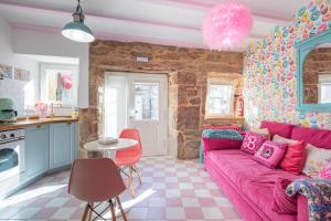 salon z różową kanapą i kuchnią w obiekcie La Suite Años 50 La casa Barbie Bañera, chimenea w mieście Corcubión