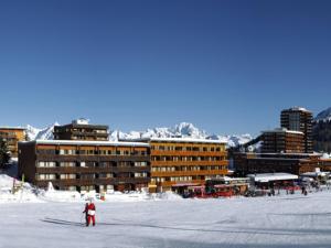 a person on skis in the snow in front of buildings at Grand studio pour 3 personnes, au pied des pistes, tout proche des commerces avec Wifi - FR-1-455-166 in La Plagne