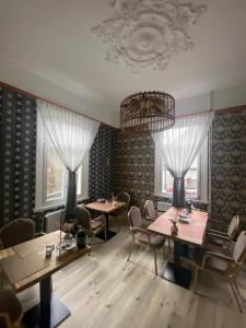 a dining room with tables and chairs and a chandelier at Villa Burgau, C&H in Monschau