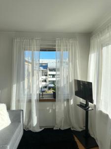 a living room with white curtains and a television at Bright Studio, Central Helsinki in Helsinki