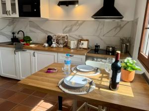 a kitchen with a wooden table with a bottle of wine at Casa Millo in Tarajalejo