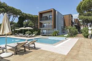 a swimming pool with chairs and a building at Hotel Gallia & Resort in Lido di Jesolo