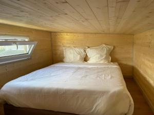 a bedroom with a white bed in a wooden room at Chalet charmant à Sainte-Marie-du-Mont avec terrasse in Sainte-Marie-du-Mont