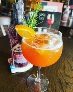a drink in a glass with an orange slice on a table at Rose and Crown B&B in Burwash
