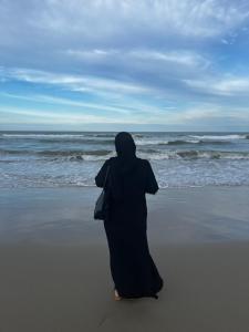 a woman standing on the beach looking at the ocean at Abah Homestay in Kuala Terengganu