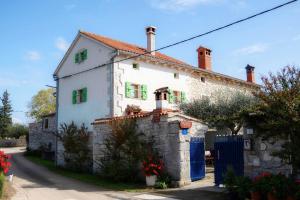 a white house with green windows on a street at Tolles Ferienhaus in Peresiji mit Privatem Pool in Peresiji