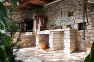 an outdoor kitchen with a stone wall at Tolles Ferienhaus in Peresiji mit Privatem Pool in Peresiji