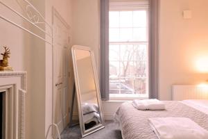 a white bedroom with a mirror next to a bed at The Bessemer Suite in Sheffield