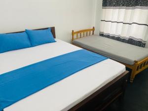 two beds in a room with blue and white at Araliya White House in Negombo