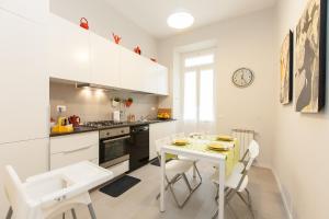 ローマにあるLovely House Romeの白いキャビネット、テーブルと椅子付きのキッチンが備わります。