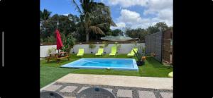 a small swimming pool in a yard with green grass at Kaz à Naja in Saint-Louis