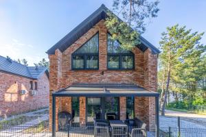 a brick house with a black roof at Sosnowy Szum Sauna 3 Wanny Spa in Jastrzębia Góra