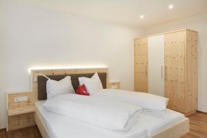 a bedroom with two white beds and a cabinet at Residence Ladurn in Tirolo
