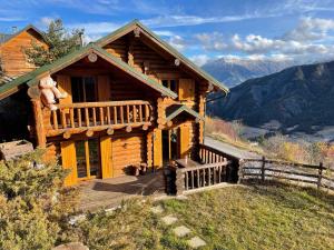 une cabane en rondins avec un ours en peluche sur la terrasse couverte dans l'établissement Chalet en rondin 8 pers. avec sauna, SPA et garage, près télécabine et navette à Praloup 1500 - FR-1-165A-126, à Uvernet