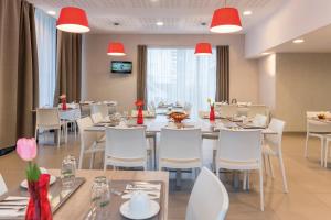 um restaurante com mesas brancas, cadeiras brancas e luzes vermelhas em Appart'City Confort Saint-Nazaire Océan em Saint-Nazaire