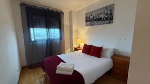 sypialnia z łóżkiem z czerwonymi poduszkami i oknem w obiekcie Apartments Madrid Suite Aeropuerto, IFEMA w Madrycie