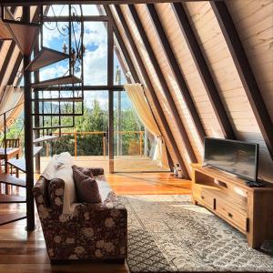 ein Wohnzimmer mit einem Sofa und einem TV auf dem Tisch in der Unterkunft Chalé Charlotte l Maravilhoso para Casal in Campos do Jordão