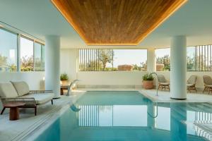 an indoor swimming pool with a table and chairs and windows at Villa Le Blanc, a Gran Meliá Hotel - The Leading Hotels of The World in Santo Tomás