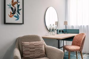 a room with a desk with a chair and a mirror at voco Winchester Hotel & Spa by IHG in Winchester