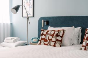 a bedroom with a bed with a blue headboard at voco Winchester Hotel & Spa by IHG in Winchester