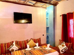 a room with a table with pillows and a tv at Dar Hassi Labied Merzouga in Adrouine