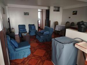 Una sala de estar con sillas azules y una mesa. en Cusco Tahuanwasi Apartments, en Cusco