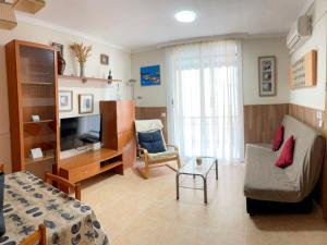 a living room with a couch a chair and a television at Apartamentos Mar Bella Segur de Calafell 3000 in Segur de Calafell