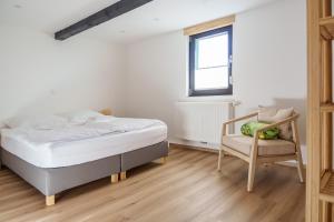 ein weißes Schlafzimmer mit einem Bett und einem Stuhl in der Unterkunft Ferienhaus Ahorn, wunderschöne, neue Wohnungen, ideal für Ausflüge ins Phantasialand, die Städte Köln, Brühl und Bonn oder die Eifel in Weilerswist