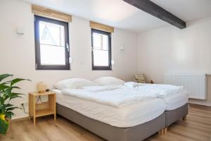 ein Schlafzimmer mit einem großen Bett mit weißer Bettwäsche in der Unterkunft Ferienhaus Ahorn, wunderschöne, neue Wohnungen, ideal für Ausflüge ins Phantasialand, die Städte Köln, Brühl und Bonn oder die Eifel in Weilerswist
