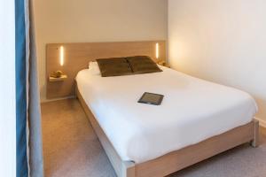 a bedroom with a bed with a book on it at Appart'City Confort Saint-Nazaire Océan in Saint-Nazaire