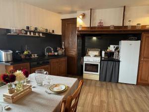a kitchen with a table and a white refrigerator at Gîte La Belle du Clocher in Saint-Pardoux-dʼArnet +10 photos