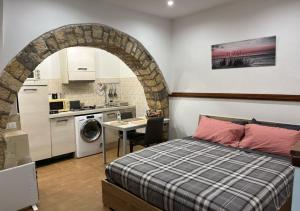 a bedroom with a bed and a kitchen with a table at La casetta di Patry in Tarquinia