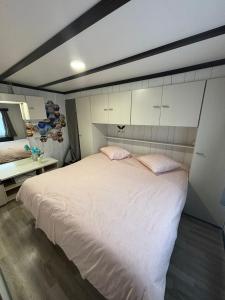 a bedroom with a large white bed with two pink pillows at Tiny Beachhouse - New Vennepark Wenduine in Wenduine