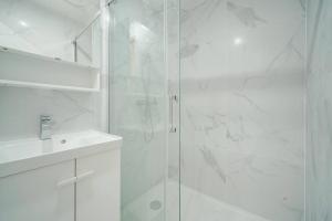 a white bathroom with a shower and a sink at Appartement Mairie des Lilas - IV in Les Lilas