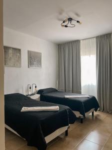 a hotel room with two beds and a window at Brisas del Lago Apartamentos in Colón