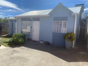 a blue house with a white door in a yard at Casita María in Puerto San Julián