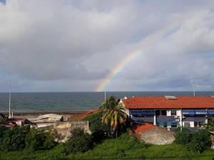 a rainbow over a house next to the ocean at Loft Temporada Praia do Meio in Natal