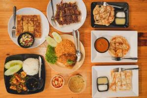 a wooden table with plates of food on it at Ben House Hatyai in Hat Yai